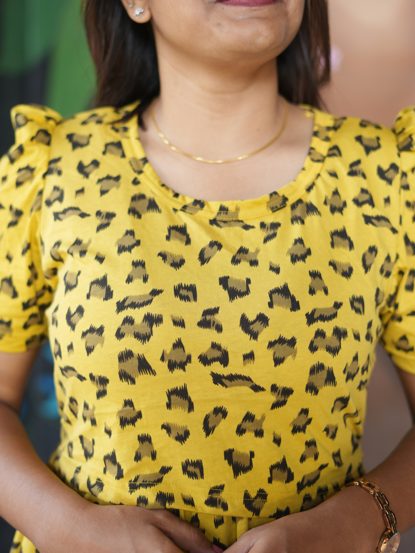 Woman wearing a yellow top with black pattern against a blurred background