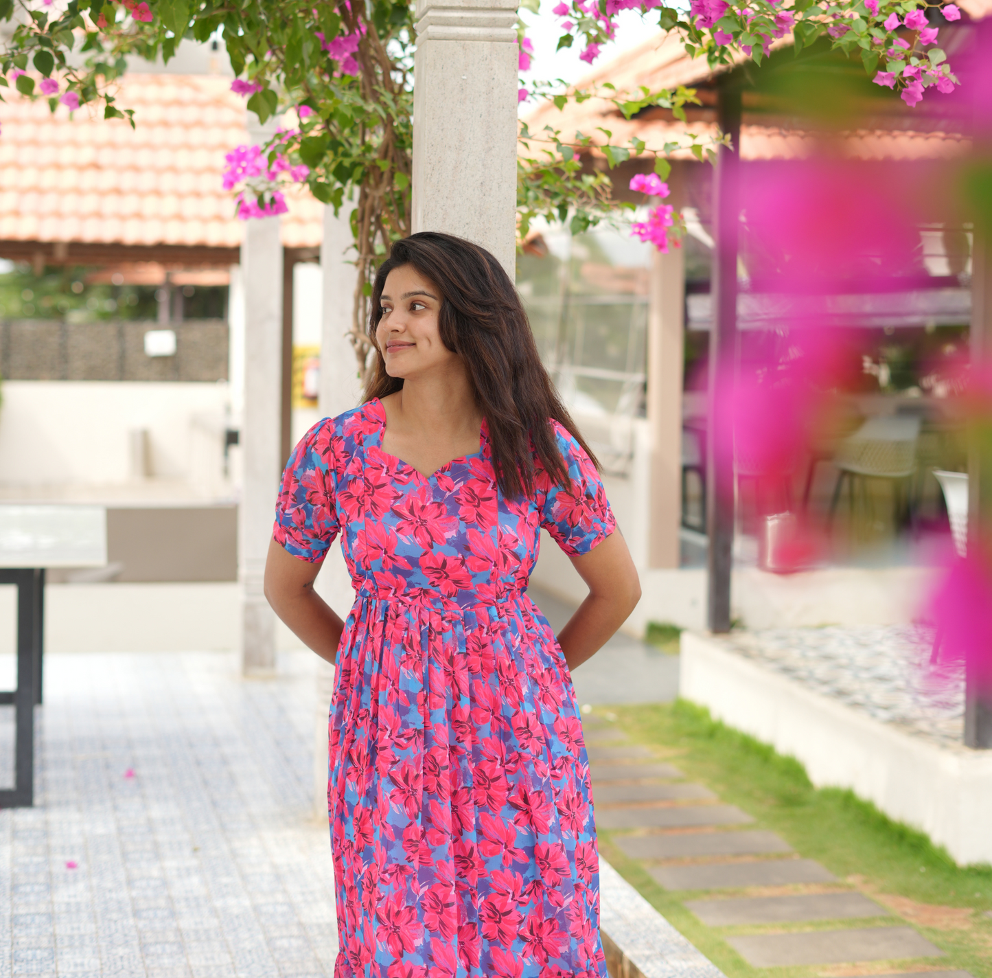 Woman in a floral dress standing under a flowering tree
