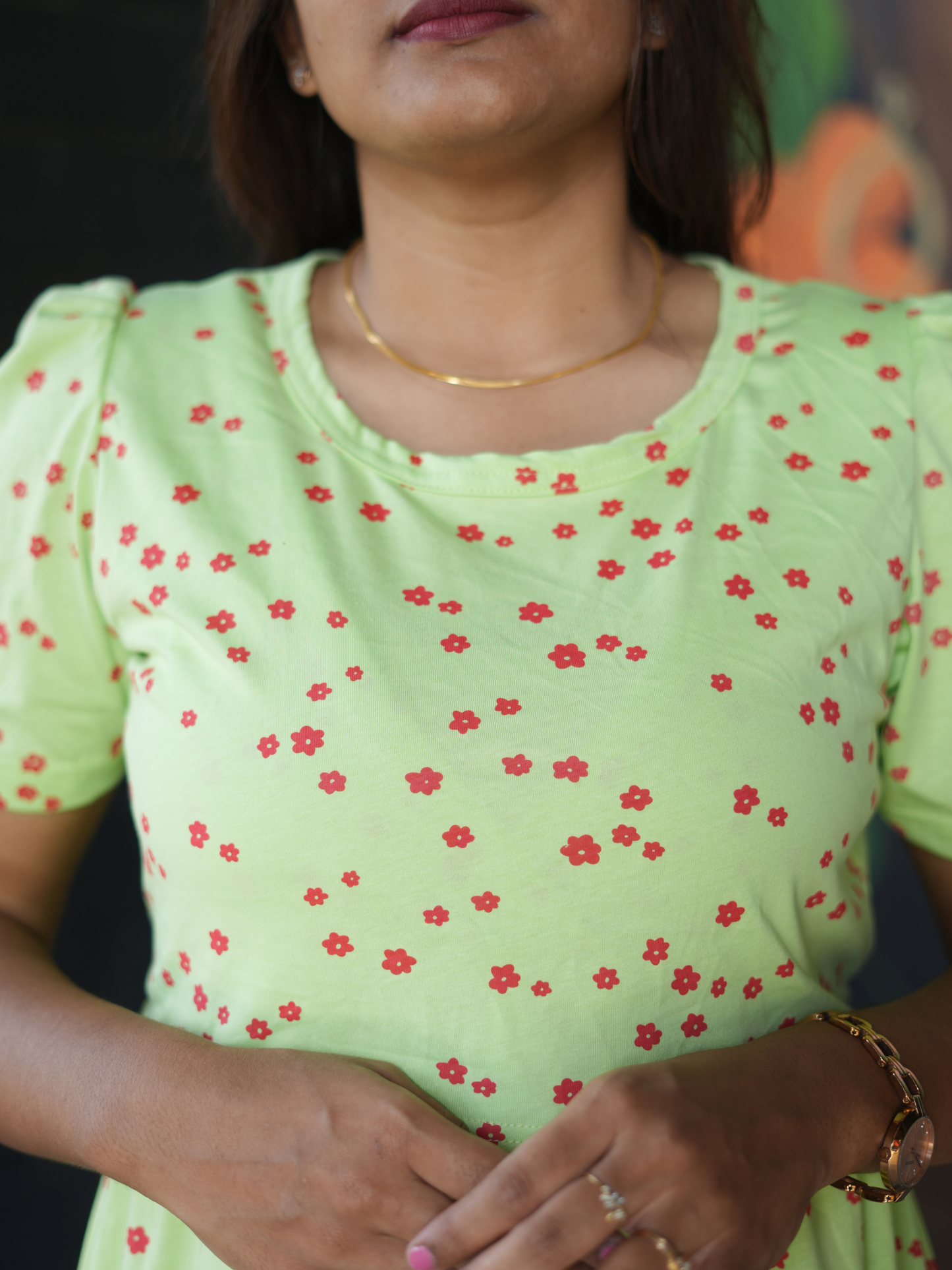 Woman wearing a light green top with red floral patterns