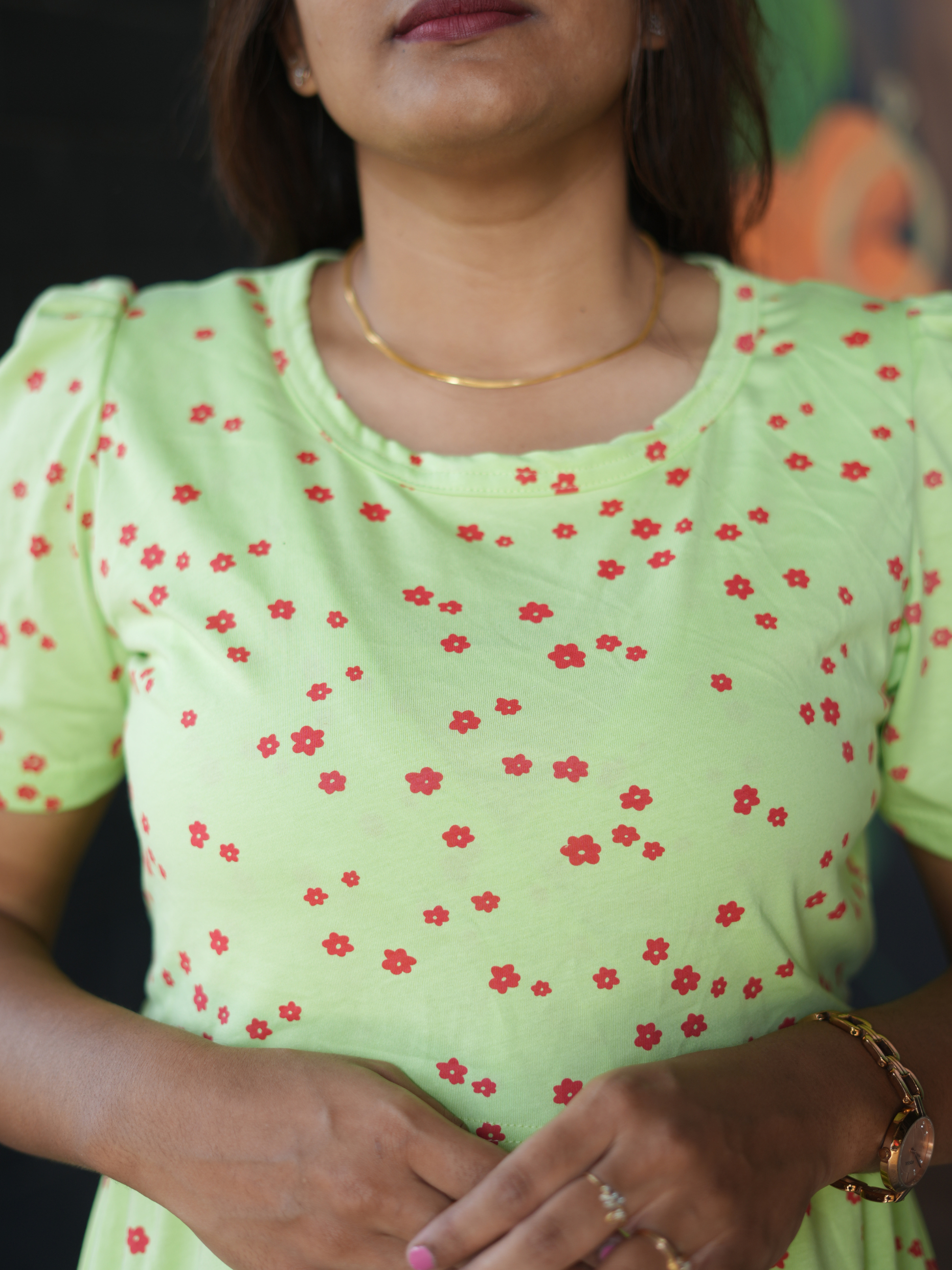 Woman wearing a light green top with red floral patterns
