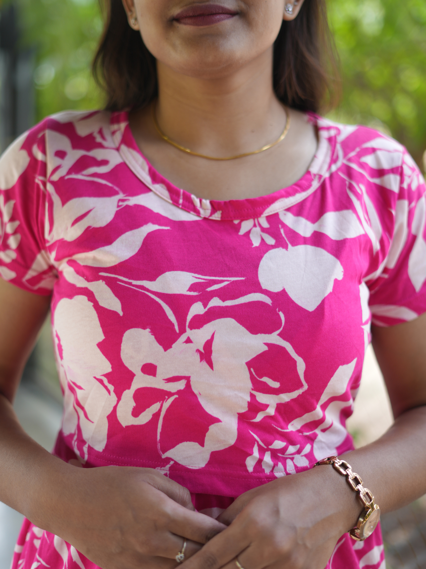 Woman wearing a pink floral top with a blurred green background