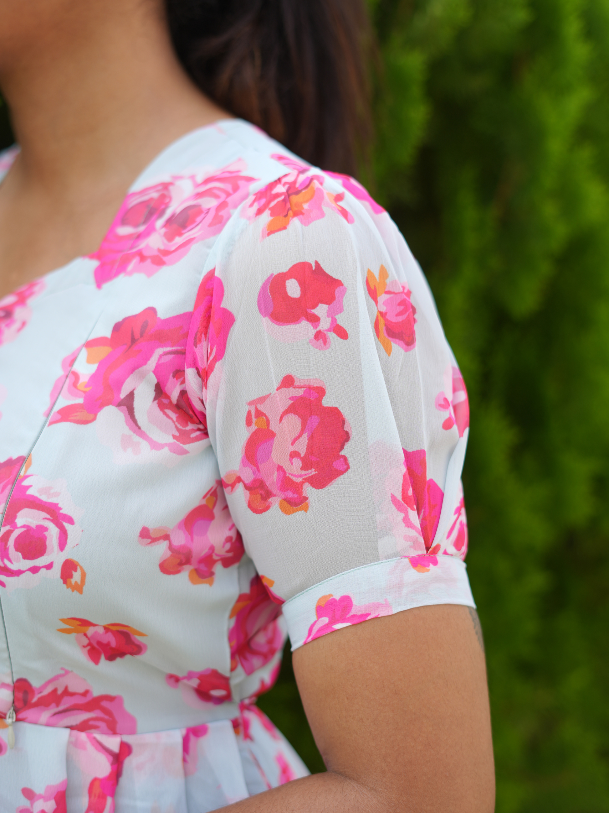 Close-up of a floral dress with pink flowers on a blurred green background