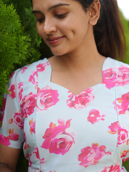Woman wearing a floral dress with pink roses against a blurred green background