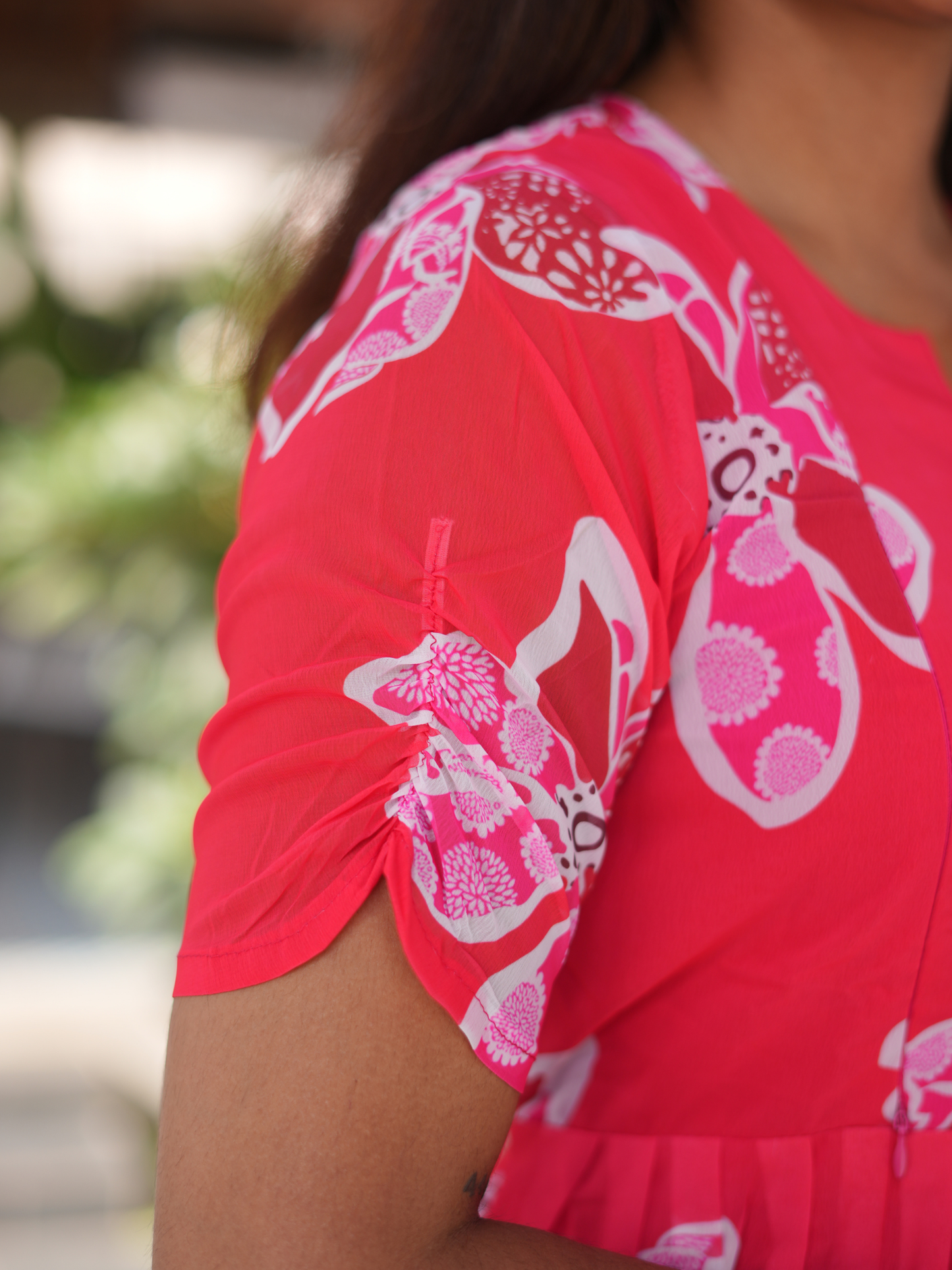 Red garment with white floral patterns worn by a person, blurred background