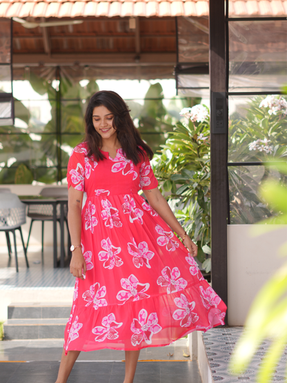 Woman wearing a red dress with pink floral patterns outdoors.