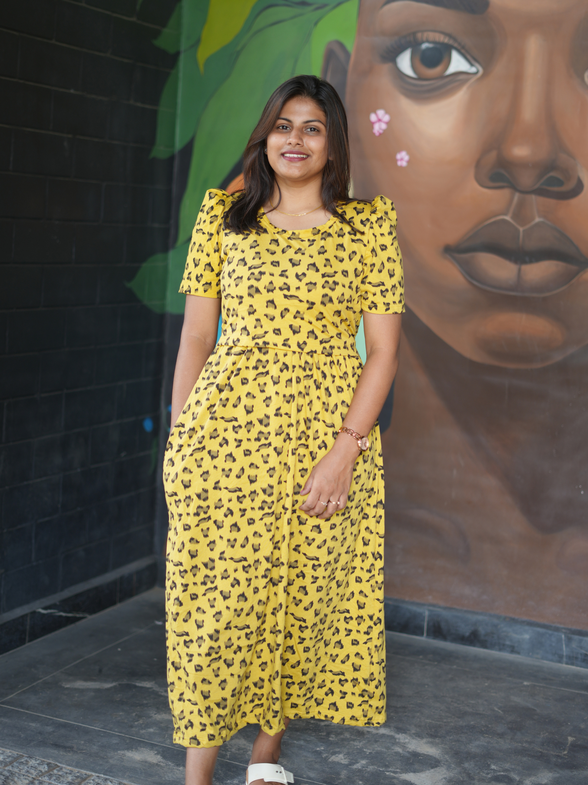 Woman in a yellow dress standing in front of a mural