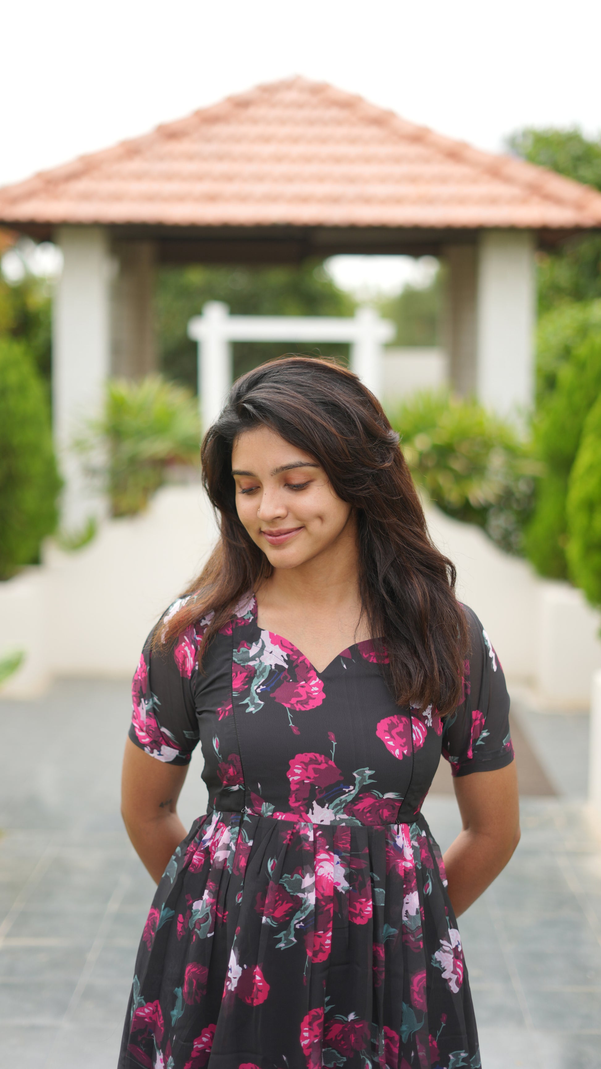 Woman wearing a floral dress standing outdoors with a gazebo in the background