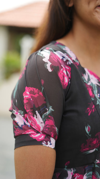 Close-up of a woman wearing a black floral dress with pink and white flowers.