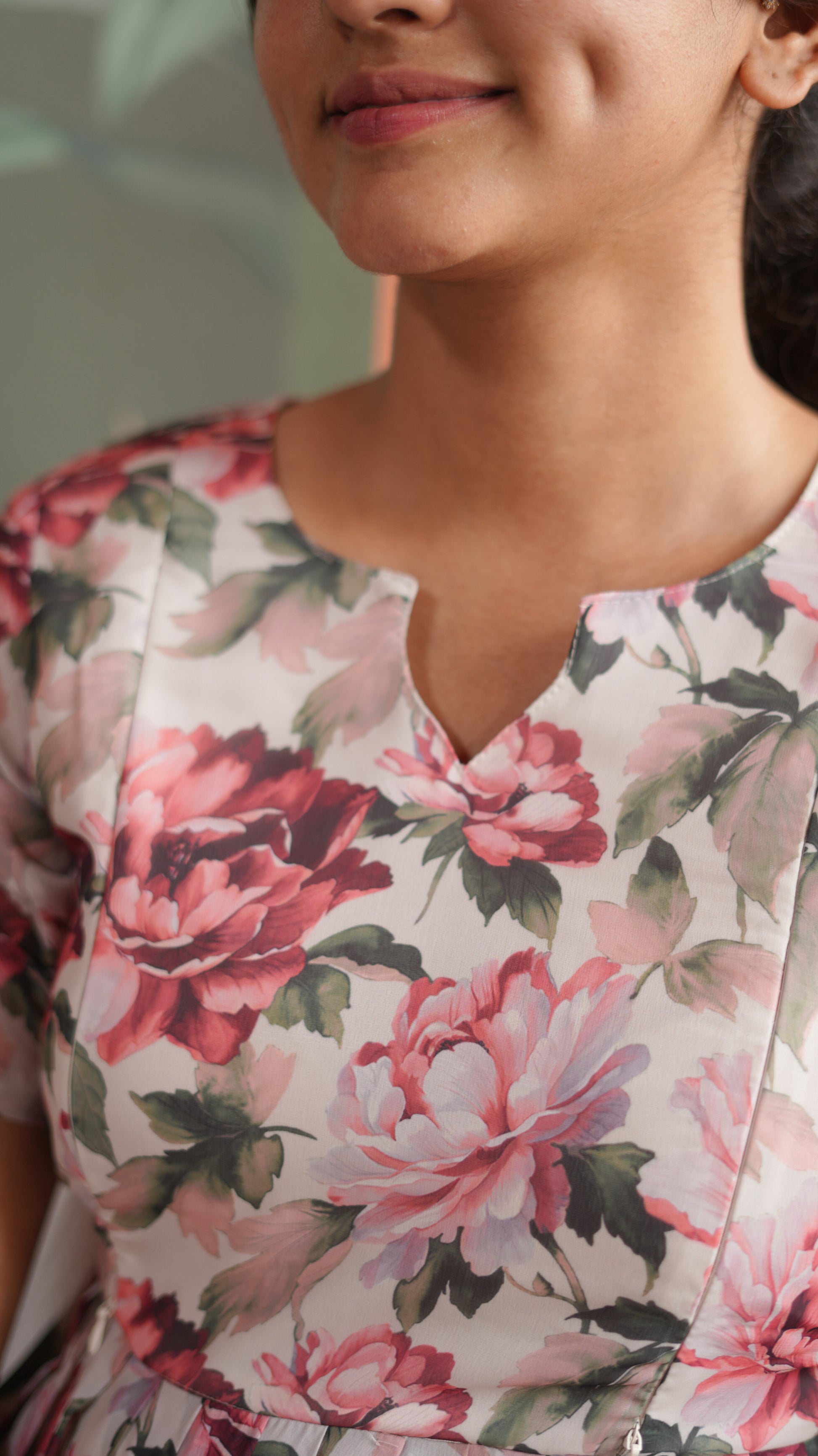 Close-up of a woman wearing a floral dress with pink and red flowers.