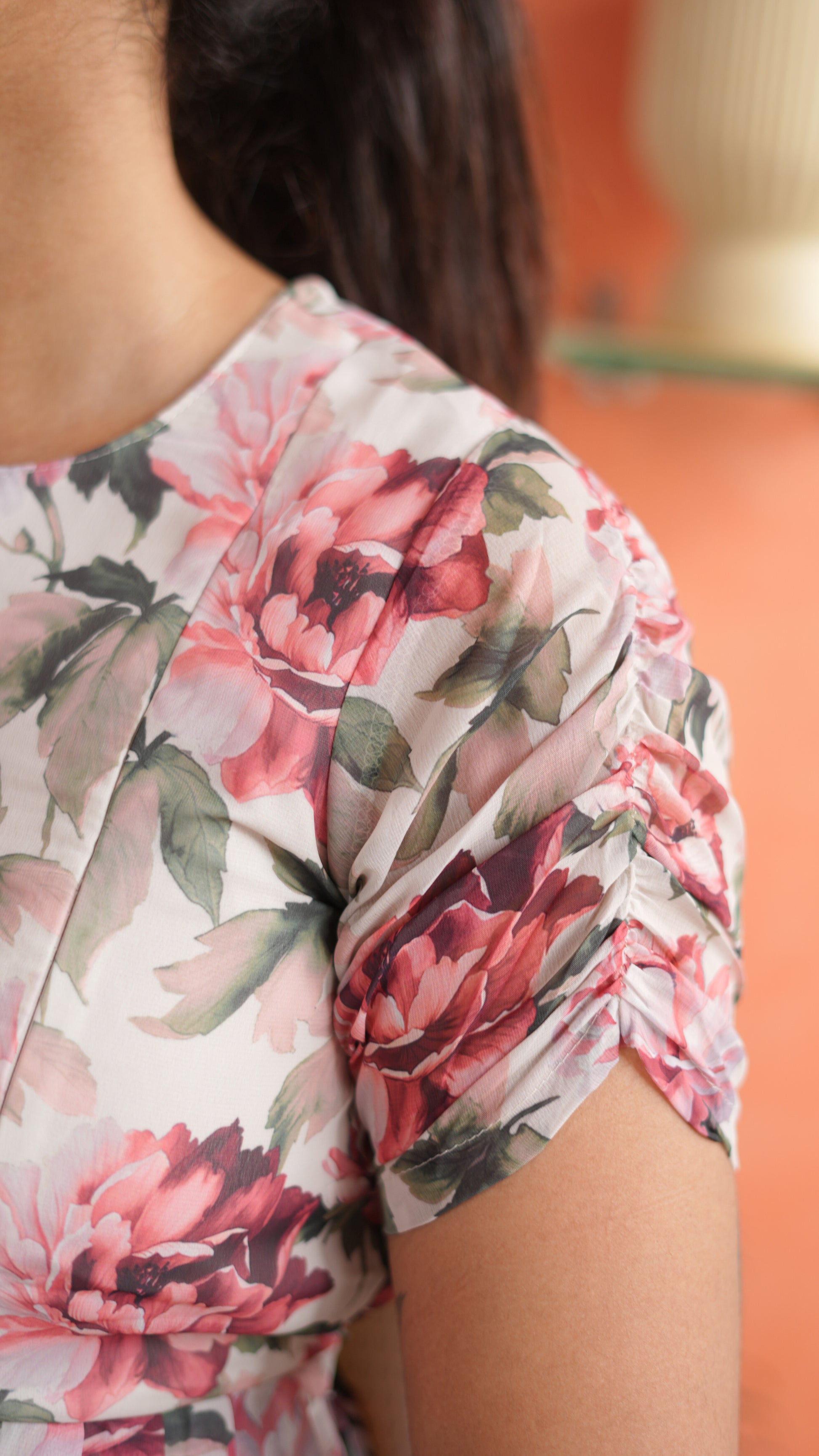 Close-up of a woman wearing a floral-patterned shirt with a blurred background