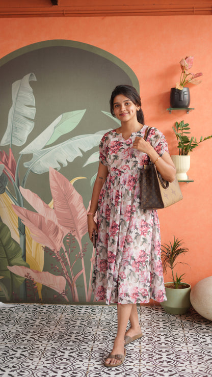 Woman in a floral dress holding a handbag against an orange wall with plant decorations