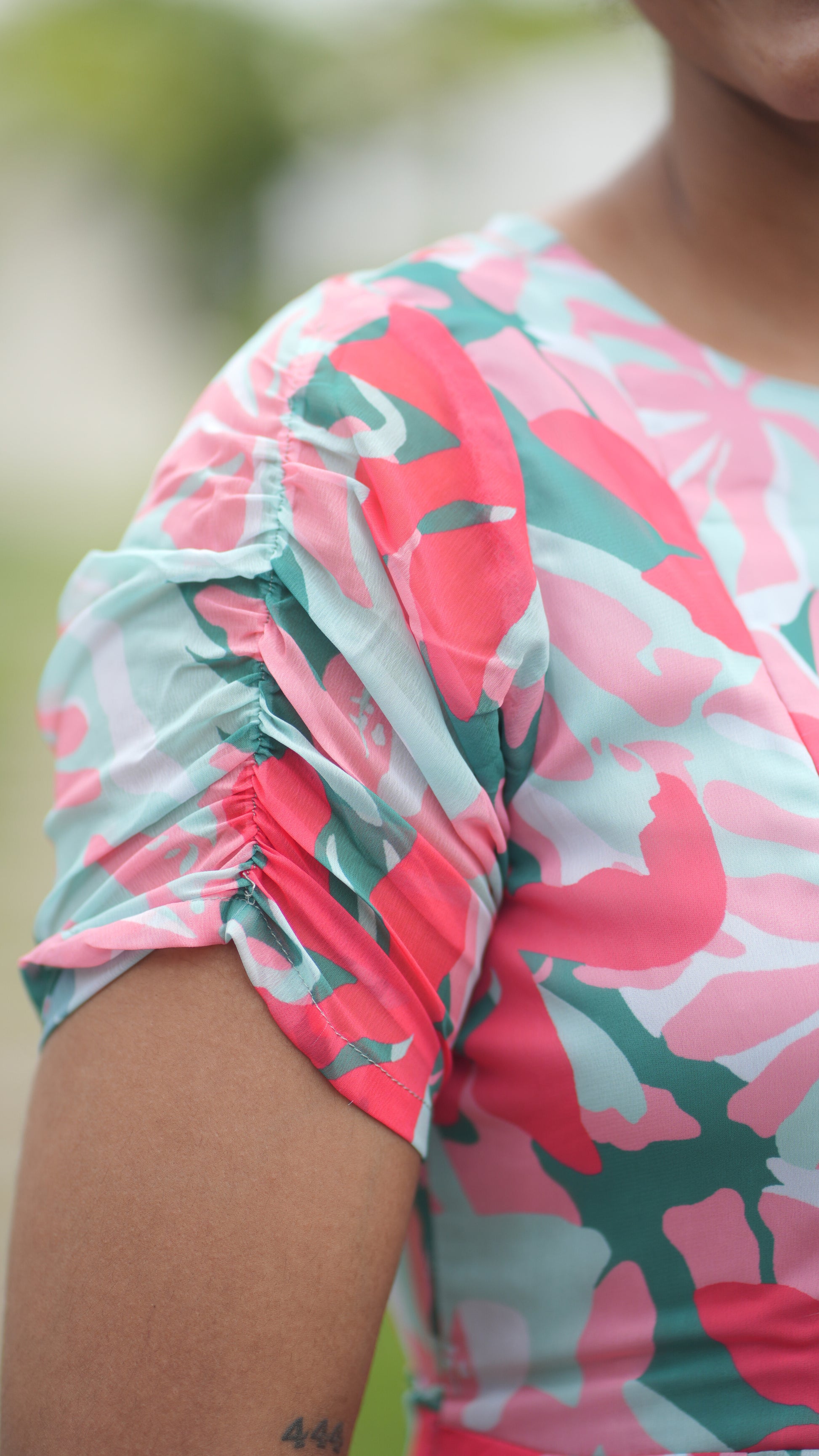 Close-up of a woman wearing a colorful floral dress with a pink and green pattern.