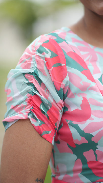 Close-up of a woman wearing a colorful floral dress with a pink and green pattern.